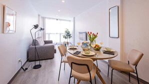 A modern living room with a round dining table, two sofas, and a floor lamp. - Sweett | Fira 302 - Two Bedroom Apartment, Sleeps 5 (Barcelona)