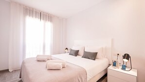 A modern hotel room with a large bed, a bedside table with a lamp, and a nightstand with a phone and a book. - Sweett | Fira 401 - Two Bedroom Apartment, Sleeps 5 (Barcelona)