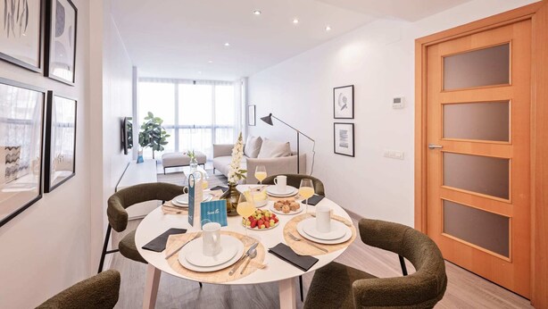 A modern dining area with a round table set for four, surrounded by dark green upholstered chairs. - Sweett | Fira 401 - Two Bedroom Apartment, Sleeps 5 (Barcelona)