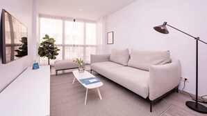 A modern living room with a sofa, a coffee table, a floor lamp, and a large window. - Sweett | Fira 401 - Two Bedroom Apartment, Sleeps 5 (Barcelona)