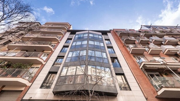 Een hoog appartementencomplex met meerdere balkons, grote ramen en een modern architectonisch ontwerp.