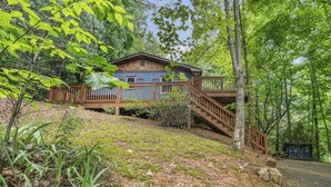 Une cabane dotée d’une terrasse en bois et d’un escalier menant à un porche abrité.