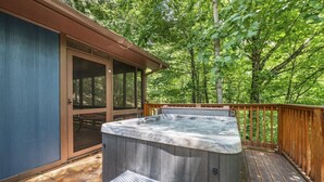Un bain à remous sur une terrasse en bois, entouré d’arbres.