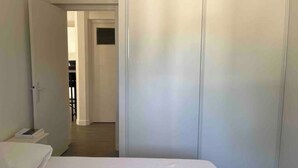 Un dormitorio con una cama, un armario blanco y una puerta que da a otra habitación.
