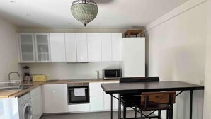 Cocina compacta con muebles blancos, microondas, lavamanos y lavadora.
