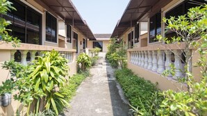 A corridor with two-story buildings, each with balconies and potted plants.