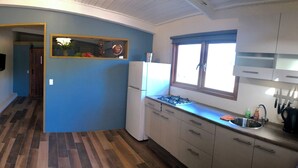 A kitchen with a stove, sink, and cabinets, a dining area with a table and chairs, and a hallway leading to another room.
