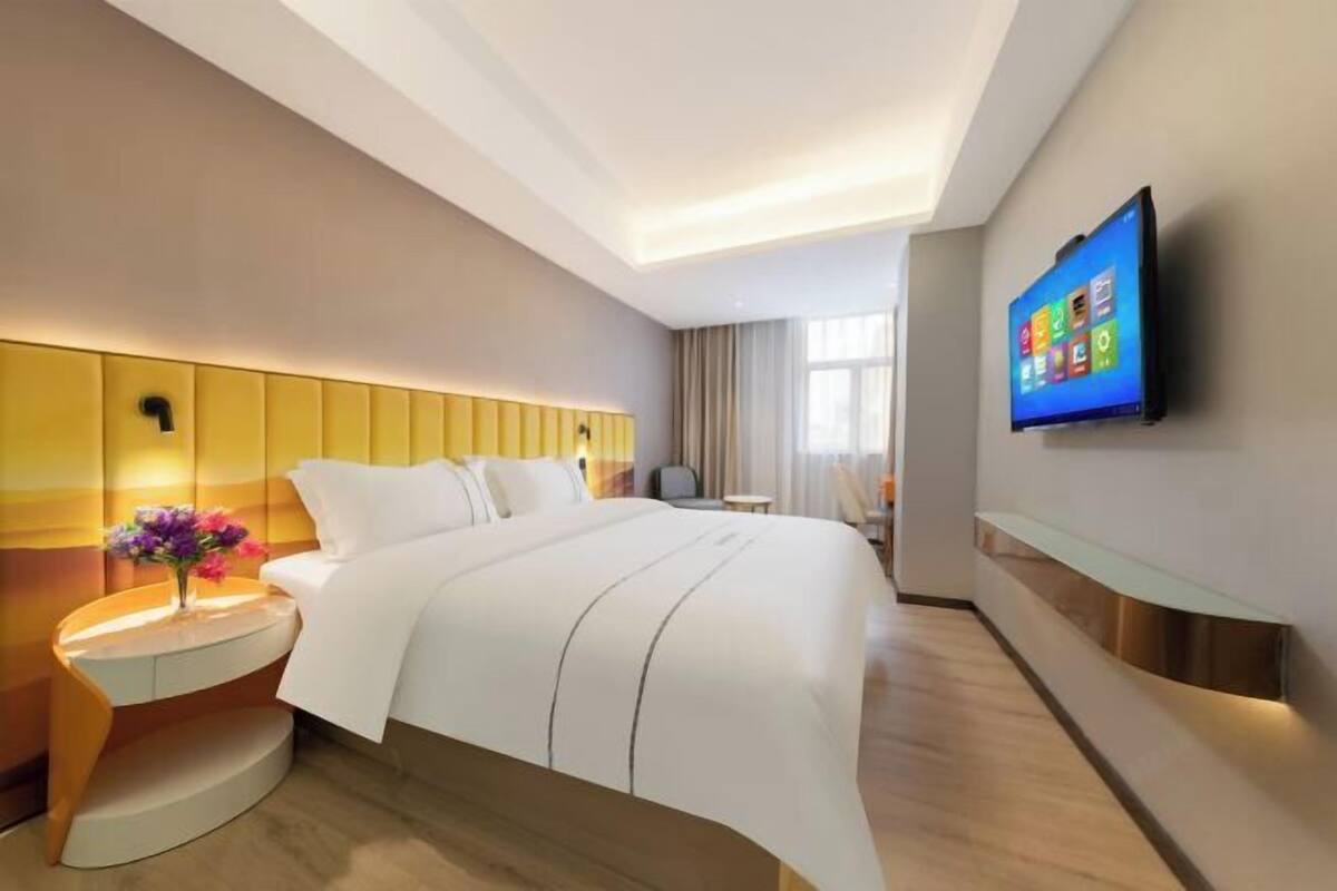 Ein modernes Hotelzimmer mit Bett, Nachttisch, Fernseher und Fenster.