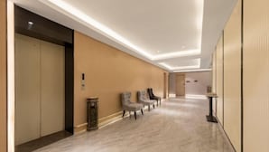 A hotel hallway with a marble floor, a reception desk, and a row of chairs. - Langfeng Capital Hotel Zhongshan (Former Sun Yat-sen · Nanlang Station Branch) (Zhongshan)