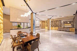 A modern hotel lobby with a reception desk, seating area, and a dining table.