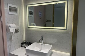 A bathroom with a white sink, a mirror with a lighted frame, and a hand dryer. - Langfeng Capital Hotel Zhongshan (Former Sun Yat-sen · Nanlang Station Branch) (Zhongshan)