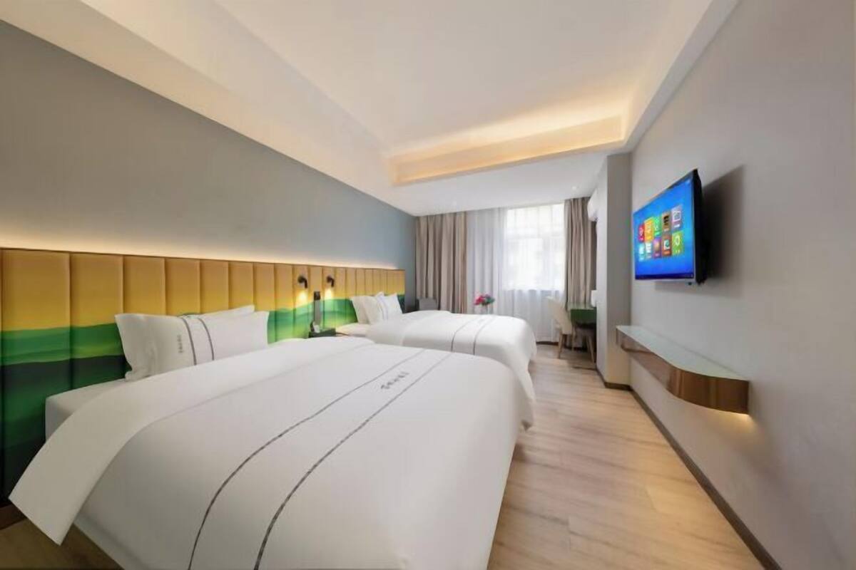 Ein Hotelzimmer mit zwei Betten, einem Fernseher und Blick ins Freie.