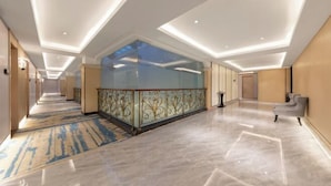 A modern hotel corridor with a glass partition, marble flooring, and a patterned carpet. - Langfeng Capital Hotel Zhongshan (Former Sun Yat-sen · Nanlang Station Branch) (Zhongshan)