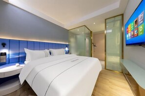 A modern hotel room with a bed, a bedside table, a TV, and a glass partition.