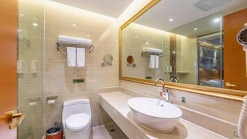 A modern bathroom with a glass shower enclosure, a white toilet, a large oval sink, and a mirror with a gold frame.