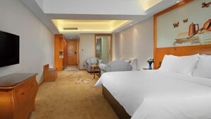 Een hotelkamer met een groot bed, een televisie, een bureau en een stoel.