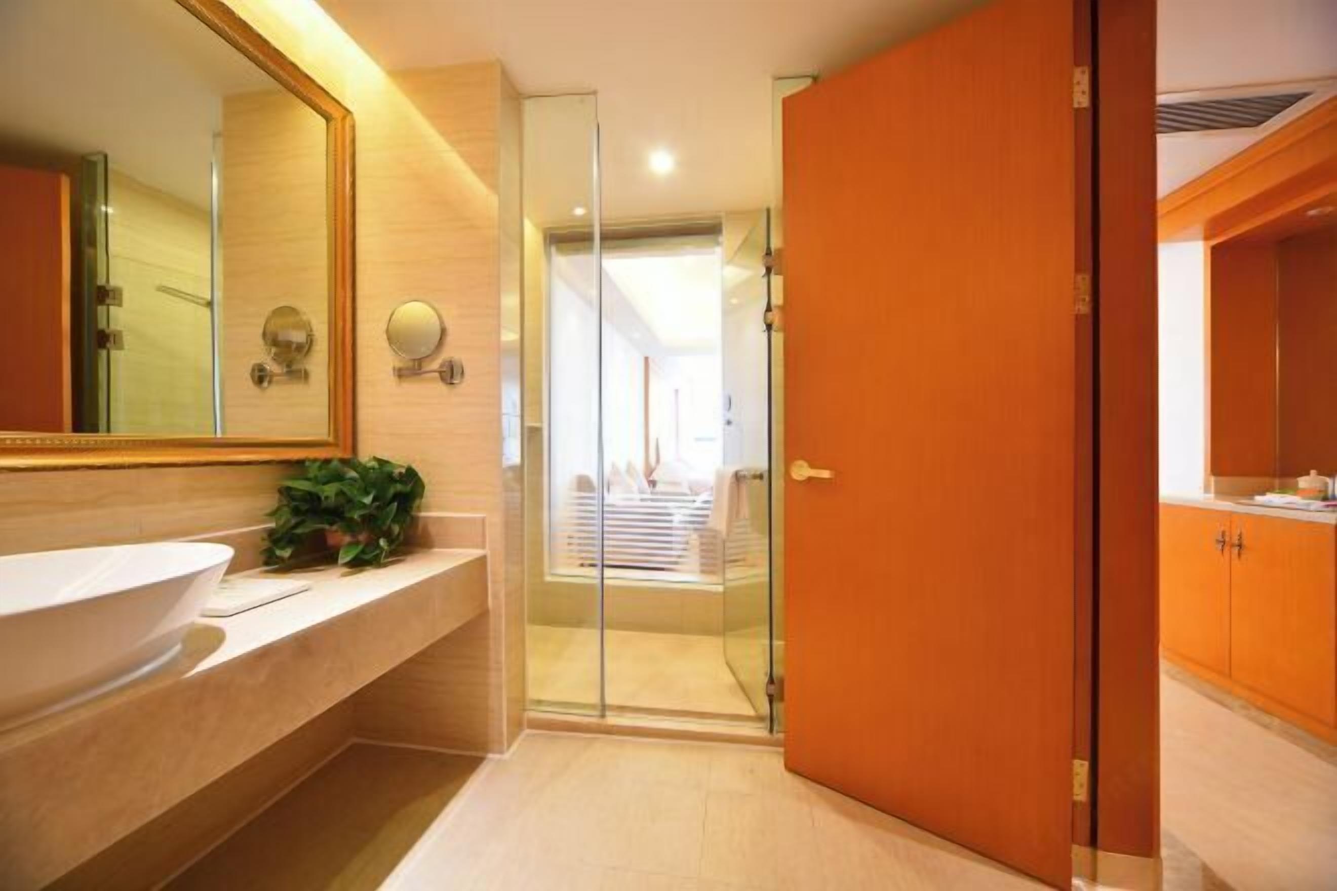 A modern bathroom with a large mirror, a white sink, and a glass shower enclosure.