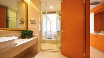 A modern bathroom with a large mirror, a white sink, and a glass shower enclosure.