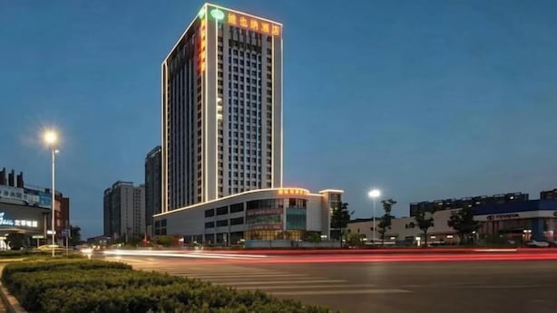 Een hoog gebouw met een modern ontwerp, met een opvallende ingang en een reeks ramen.