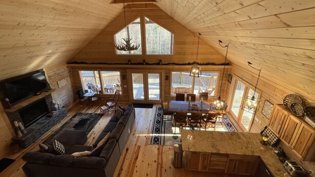 A cabin interior with a loft dining area, a living room with a sofa, and a kitchen with a countertop. - Beautiful New Cabin on the Broad River, 3 miles from Lake Lure, NC (Lake Lure)