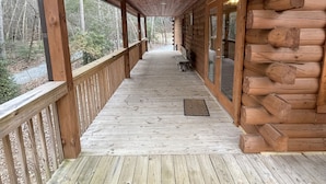 A wooden deck with a railing, a covered porch, and a view of the surrounding forest. - Beautiful New Cabin on the Broad River, 3 miles from Lake Lure, NC (Lake Lure)