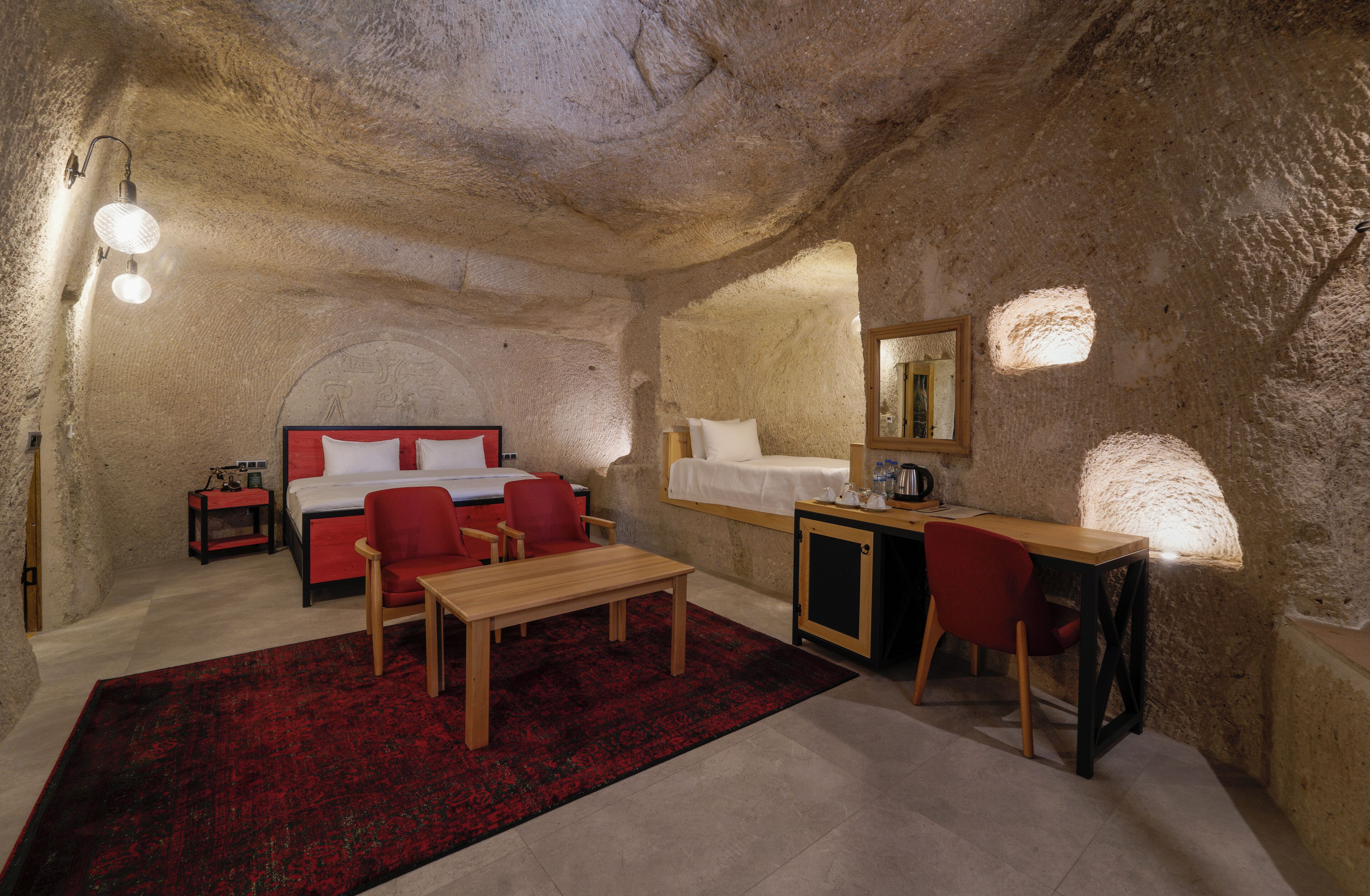 Una habitación acogedora con cama, escritorio y silla, que presenta un tapete rojo y una mesa de madera.