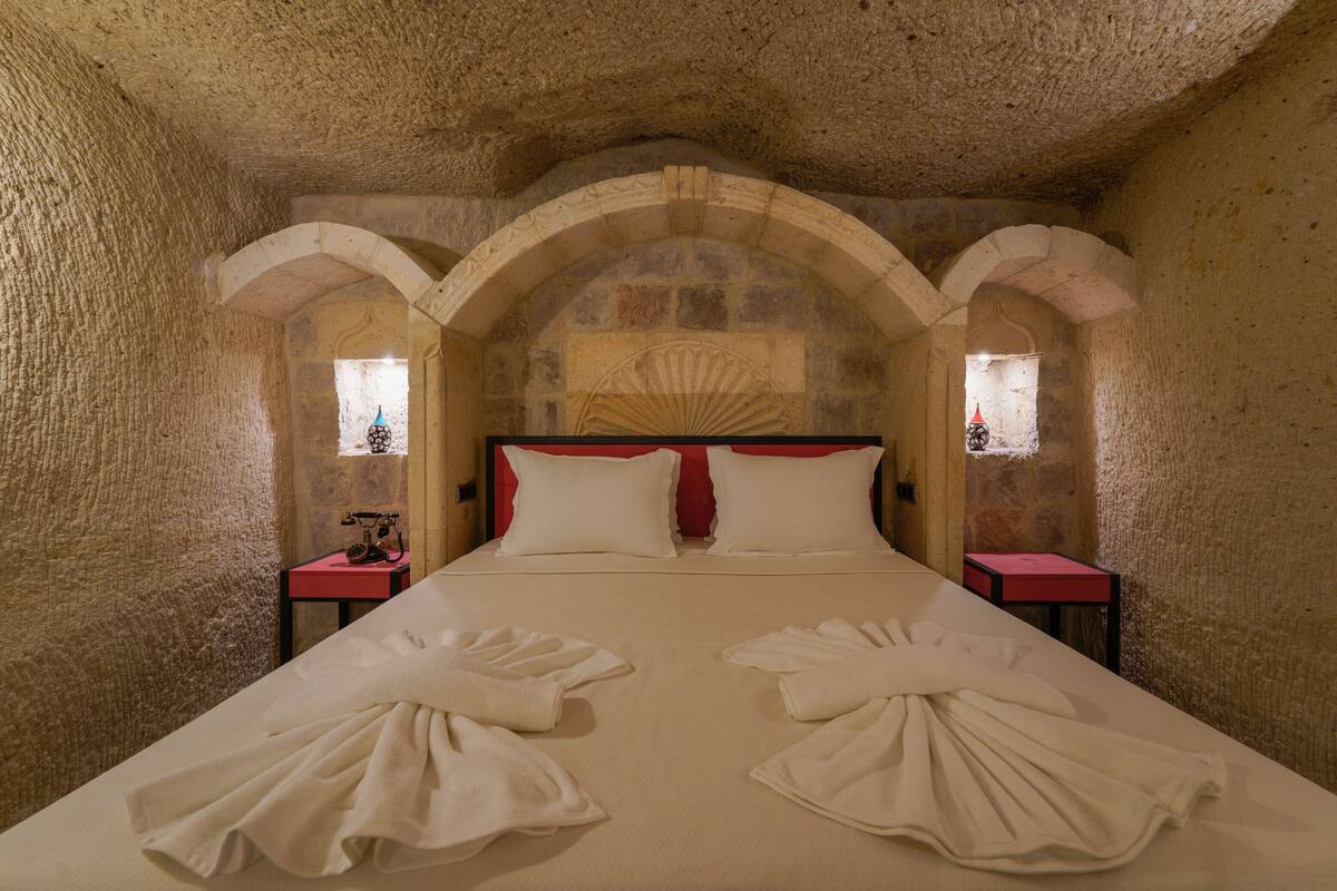 A bed with white linens and towels, stone walls, and arched ceilings.