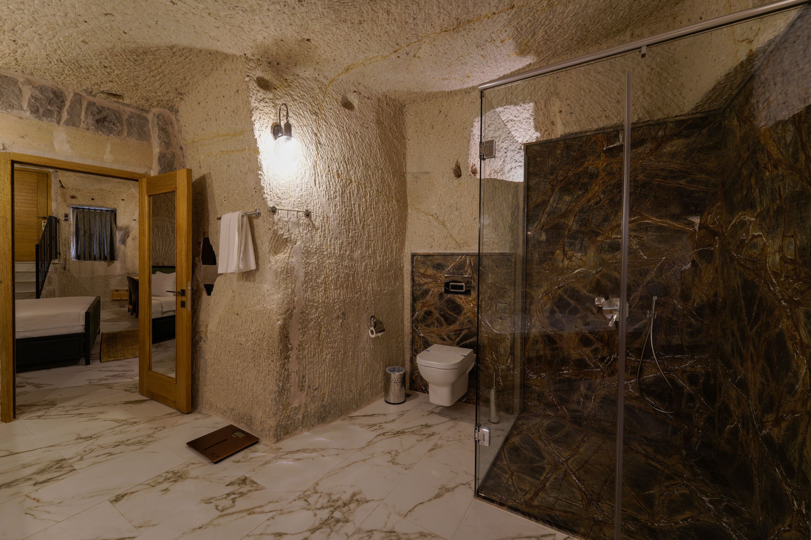 A bathroom with a stone wall, a glass shower enclosure, a toilet, and a sink.