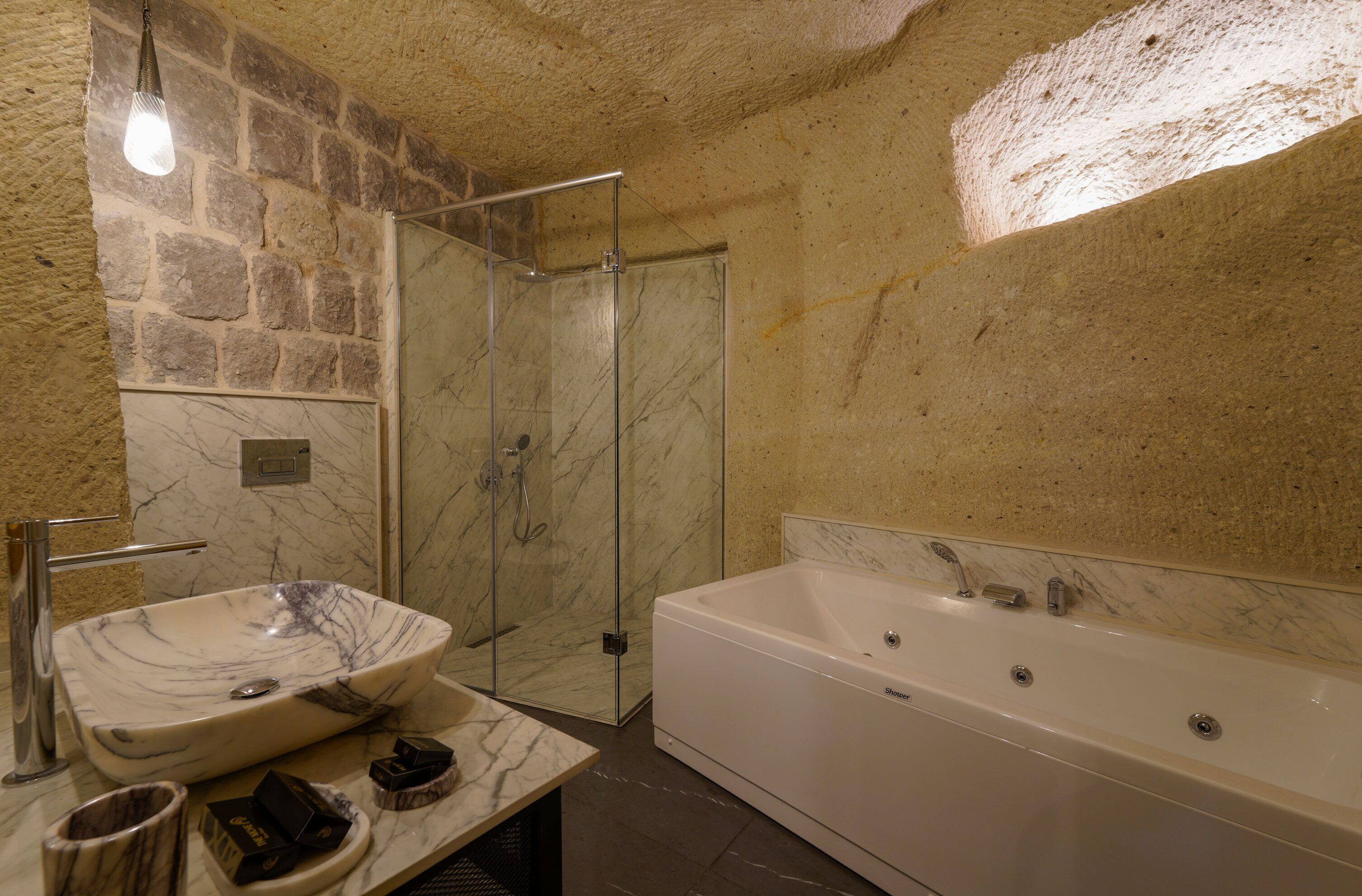 Une salle de bain avec un lavabo en marbre, une baignoire et une cabine de douche en verre.