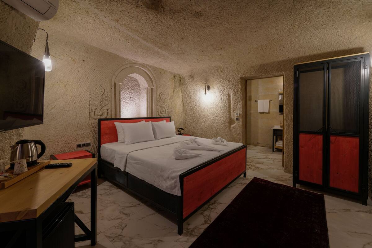 A bedroom with a bed, a desk, a TV, and a wardrobe.