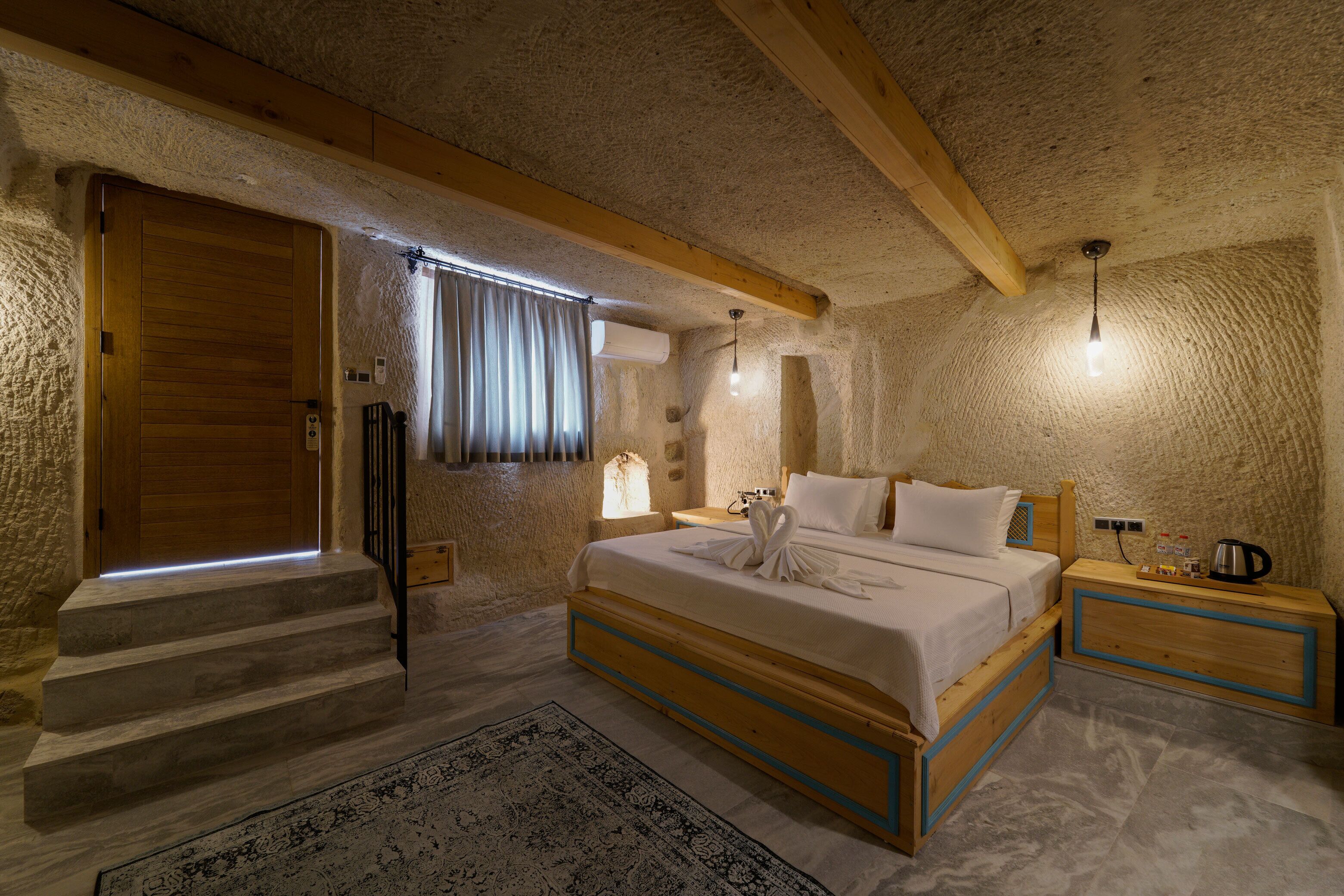 A bedroom with a wooden bed, a nightstand, a window with curtains, and a staircase.