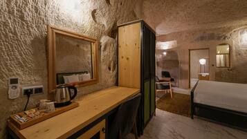 Een rustieke kamer met een houten bureau, een bed en een spiegel.