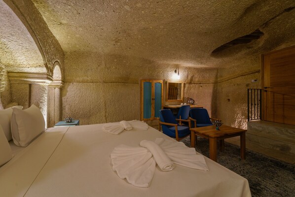 A room with a bed, a desk, and two chairs. - The Niche Cave Hotel (Nevsehir)
