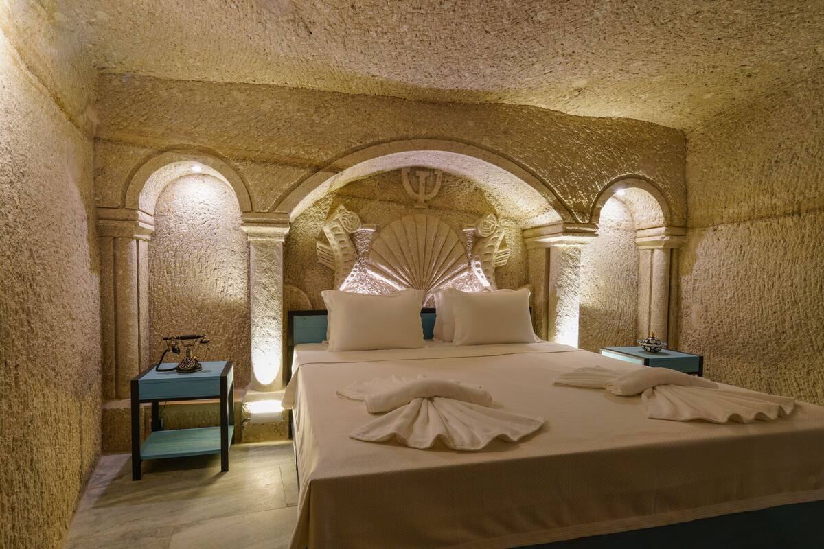 A room with a large bed, two bedside tables, and a decorative arched ceiling.