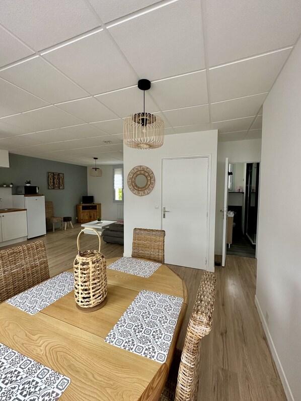 Una sala moderna con una mesa de comedor de madera, sillas de mimbre y una lámpara colgante.
