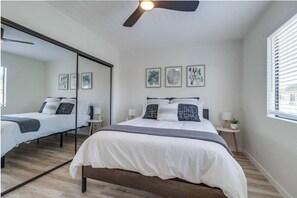 Une chambre dotée d’un grand lit, de tables de chevet, d’un ventilateur de plafond et d’œuvres d’art murales.