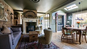 A cozy living room with a fireplace, a sofa, a dining table with chairs, and a patterned rug. - Beautiful and spacious Edwardian home by the seaside (Worthing)
