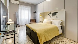 A modern bedroom with a bed, bedside table, lamp, and a world map on the wall. - BDC - Termini Studio (Roma)