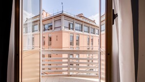 Vista desde un balcón con baranda blanca, que da a un edificio de varios pisos y balcones.
