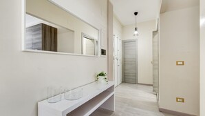 Un pasillo con una consola blanca, un espejo grande y una puerta con interruptor de luz.