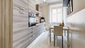 Una cocina moderna con comedor, que incluye horno empotrado, microondas y una mesa con sillas.