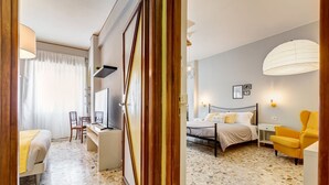 Une chambre d’hôtel avec un lit, un bureau, une chaise, une télévision et une lampe.