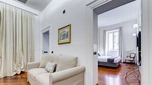 A modern hotel room with a sofa, a bed, a framed picture, and a view of the outside.