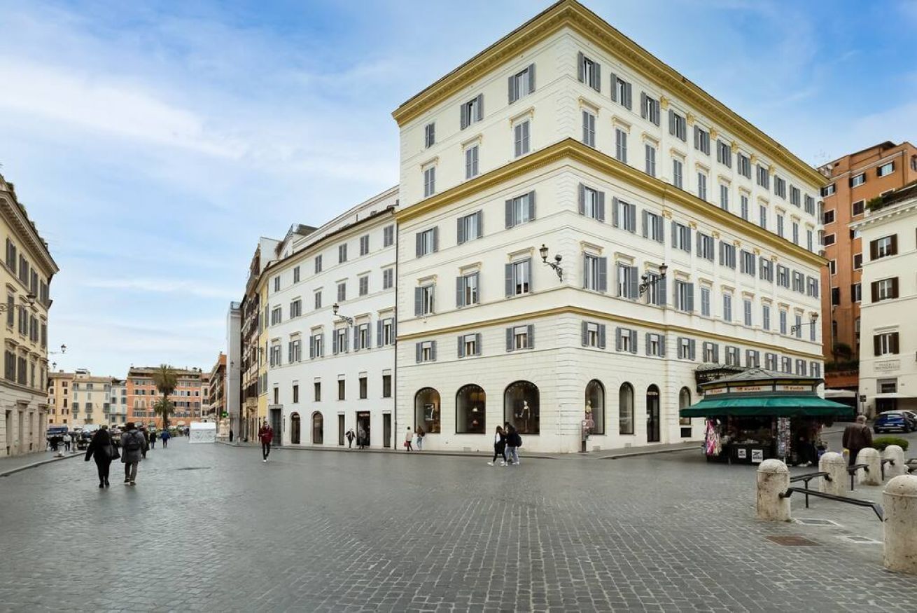 A historic building with a central courtyard, arched doorways, and a street-side kiosk.