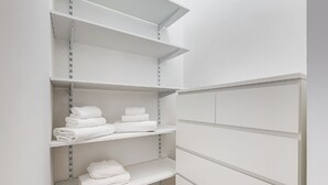A white storage closet with shelves, some containing folded white towels. - BDC - Termini Sunrise Apartment (Roma)