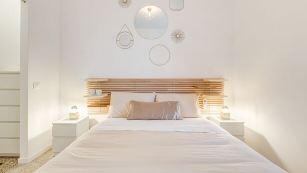 A bedroom with a bed, bedside tables, a headboard, and wall decorations. - BDC - Termini Sunrise Apartment (Roma)