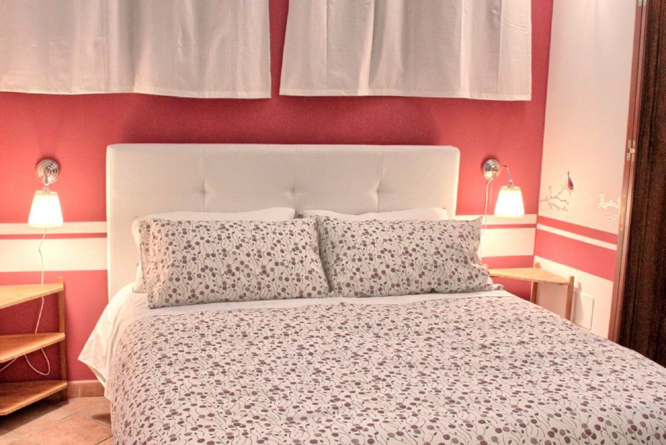 A bed with a floral bedspread, two bedside lamps, and a white headboard.