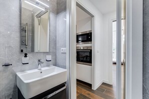 Un bagno moderno con un lavandino bianco, uno specchio e un porta asciugamani.
