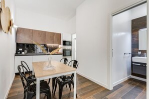 Una cucina moderna con tavolo e sedie, forno a microonde, forno e un armadietto bianco.