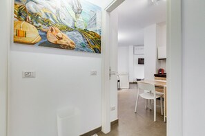A modern interior with a dining area, a kitchen, and a hallway leading to another room.